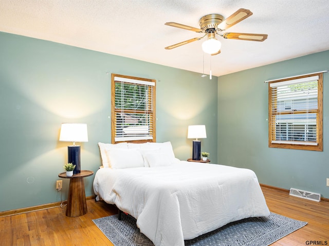 bedroom featuring wood finished floors, baseboards, and a ceiling fan