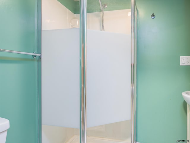 full bath featuring a shower with shower door and toilet