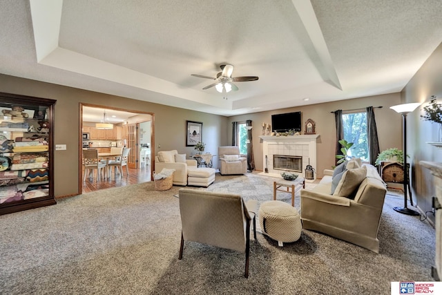 1714 S 14th Circle Dr, Beatrice, NE 68310 - living room with a raised ceiling, carpet floors, a fireplace, ceiling fan, and a textured ceiling