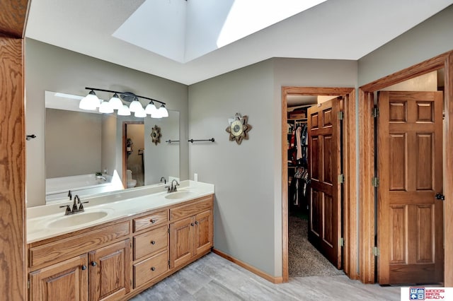 1714 S 14th Circle Dr, Beatrice, NE 68310 - bathroom featuring double vanity, a walk in closet, a garden tub, and baseboards