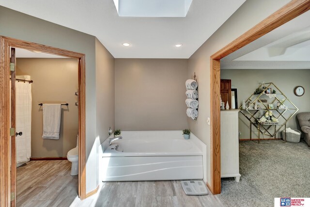 1714 S 14th Circle Dr, Beatrice, NE 68310 - bathroom featuring toilet, a bath, wood finished floors, baseboards, and recessed lighting