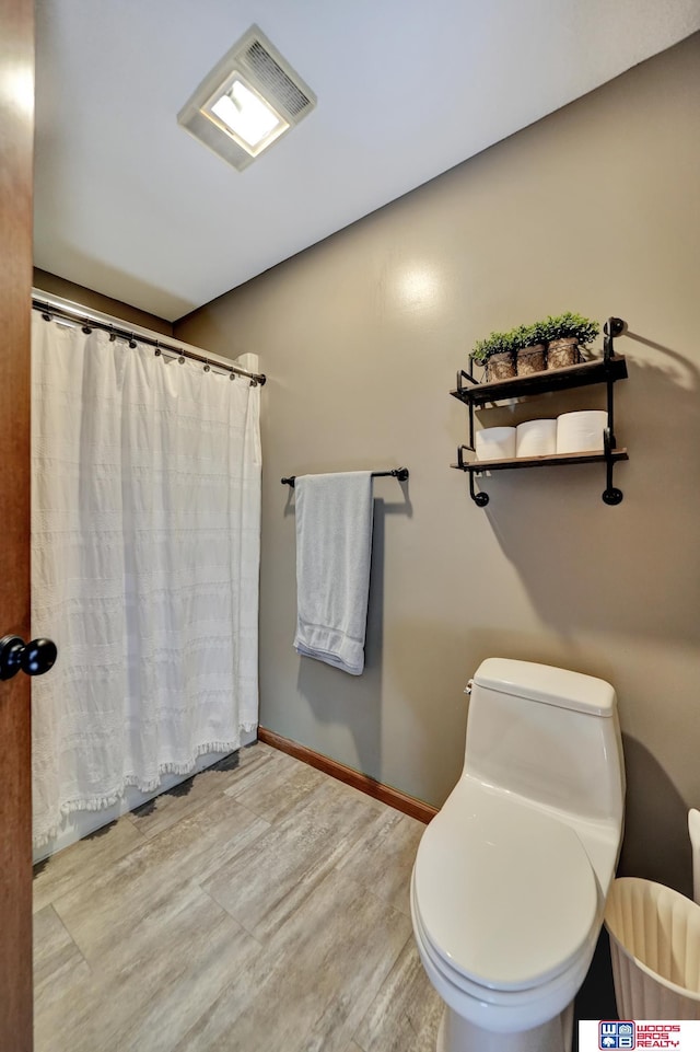 1714 S 14th Circle Dr, Beatrice, NE 68310 - full bath with wood finished floors, toilet, baseboards, and a shower with shower curtain