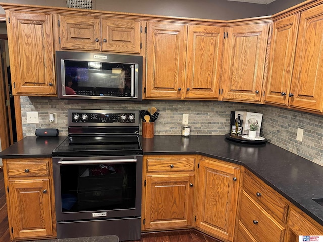 1714 S 14th Circle Dr, Beatrice, NE 68310 - kitchen with stainless steel electric stove, dark countertops, backsplash, and brown cabinets