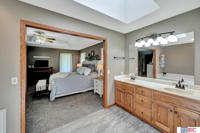1714 S 14th Circle Dr, Beatrice, NE 68310 - bathroom featuring ensuite bath, a skylight, double vanity, ceiling fan, and wood finished floors