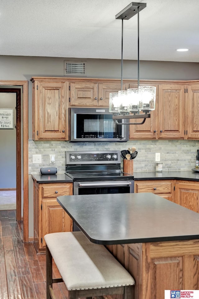 1714 S 14th Circle Dr, Beatrice, NE 68310 - kitchen with stainless steel appliances, dark countertops, backsplash, and dark wood-style floors