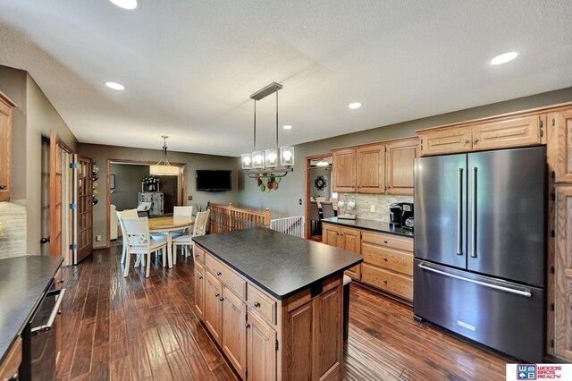 1714 S 14th Circle Dr, Beatrice, NE 68310 - kitchen featuring high end refrigerator, dark countertops, backsplash, dark wood-type flooring, and decorative light fixtures