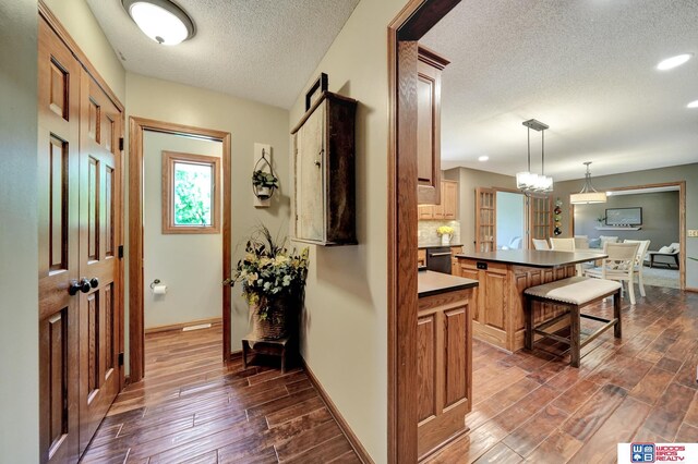 1714 S 14th Circle Dr, Beatrice, NE 68310 - kitchen featuring a textured ceiling, dark wood-style flooring, baseboards, dark countertops, and a breakfast bar area
