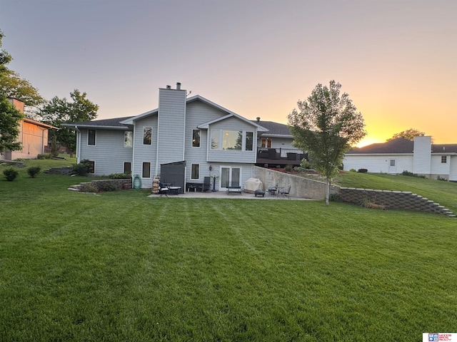 1714 S 14th Circle Dr, Beatrice, NE 68310 - rear view of house featuring a patio area, a lawn, and a chimney