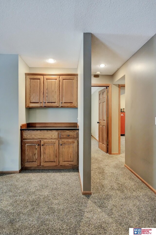 1714 S 14th Circle Dr, Beatrice, NE 68310 - kitchen with light carpet, baseboards, a textured ceiling, dark countertops, and recessed lighting