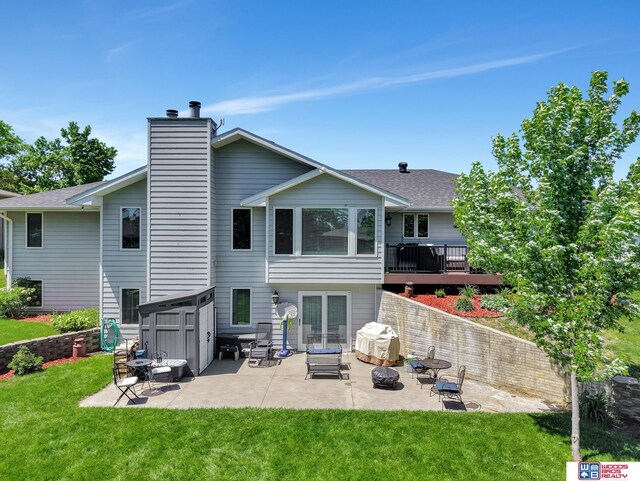 1714 S 14th Circle Dr, Beatrice, NE 68310 - rear view of house with a lawn, a patio, a chimney, a shingled roof, and a deck