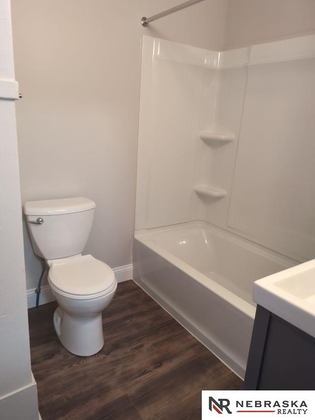 1941 J St, Lincoln, NE 68510 - bathroom with baseboards, toilet, wood finished floors, bathing tub / shower combination, and vanity