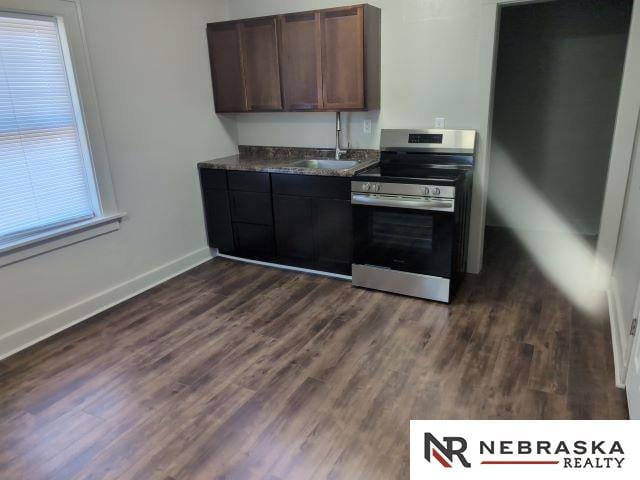 1941 J St, Lincoln, NE 68510 - kitchen featuring stainless steel electric stove, a sink, dark countertops, dark wood-style flooring, and baseboards