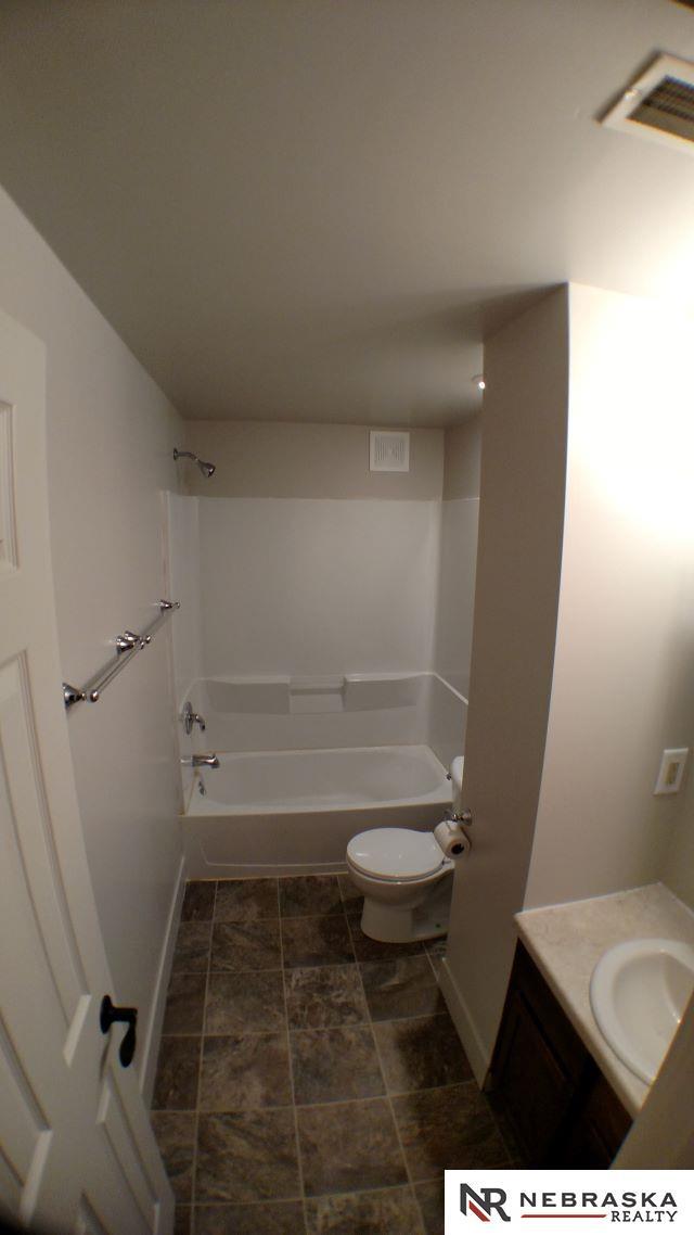 1941 J St, Lincoln, NE 68510 - bathroom with toilet, vanity, baseboards, and shower / bath combination