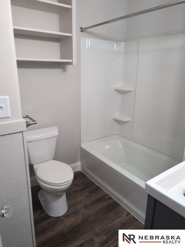 1941 J St, Lincoln, NE 68510 - full bath featuring wood finished floors, toilet, baseboards, and bathtub / shower combination