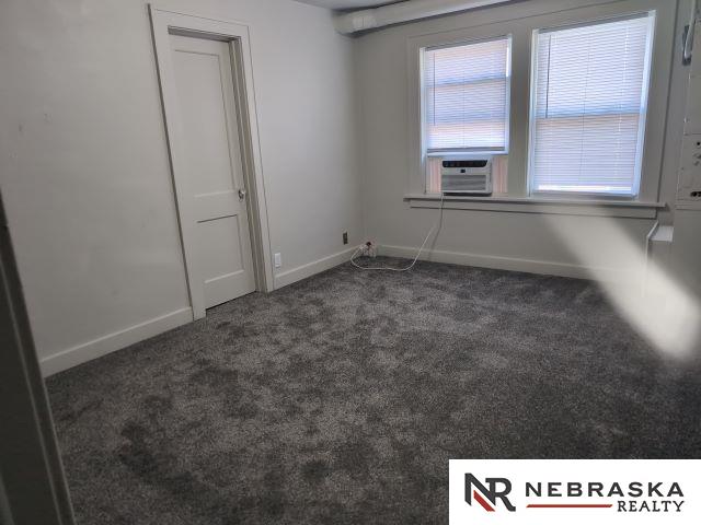 1941 J St, Lincoln, NE 68510 - empty room featuring carpet floors, baseboards, and cooling unit