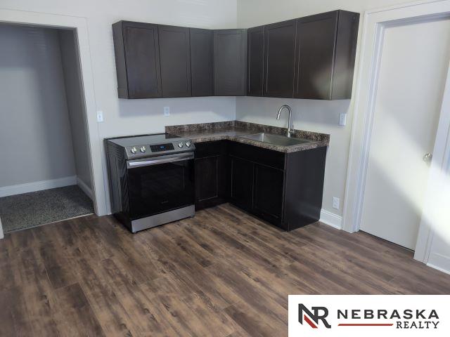 1941 J St, Lincoln, NE 68510 - kitchen featuring stainless steel electric range oven, a sink, dark wood-type flooring, and dark countertops