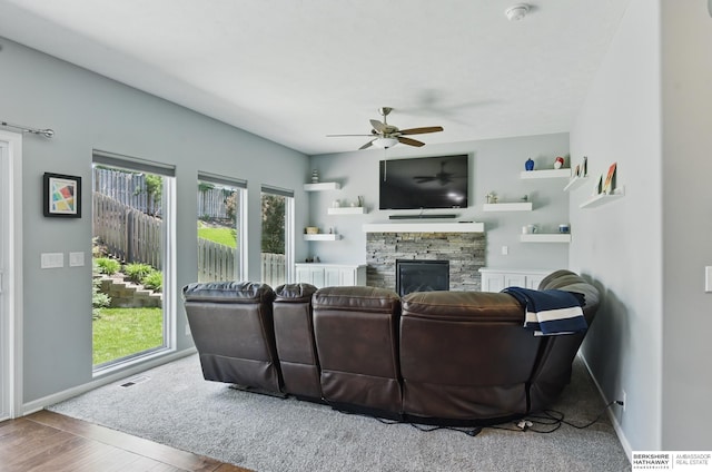 living room featuring a ceiling fan, a fireplace, wood finished floors, and baseboards