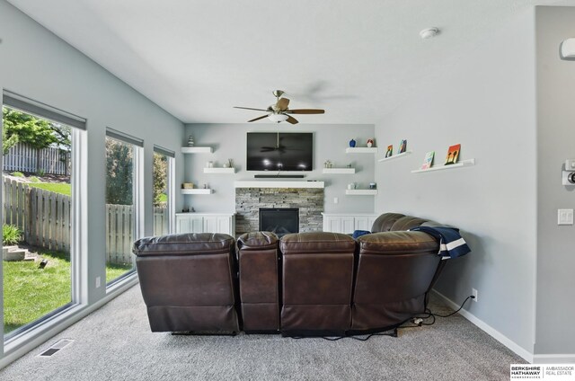 carpeted living area with ceiling fan, a fireplace, and baseboards