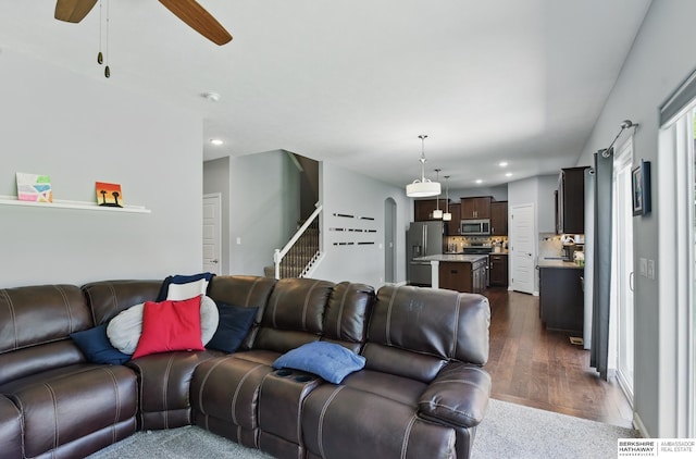 living room featuring dark wood-style floors, ceiling fan, recessed lighting, arched walkways, and stairs