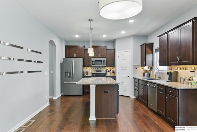 kitchen with stainless steel appliances, a sink, dark brown cabinetry, recessed lighting, and backsplash