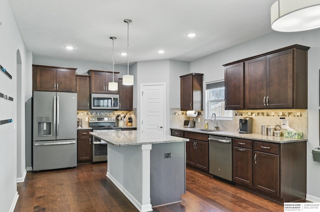 kitchen featuring appliances with stainless steel finishes, a sink, dark brown cabinetry, a center island, and recessed lighting