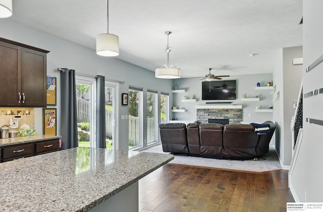 living room featuring a ceiling fan, dark wood finished floors, a fireplace, and baseboards