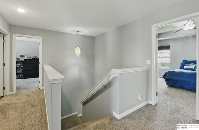 hall with an upstairs landing, carpet floors, and baseboards