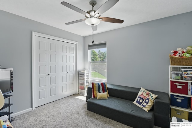 living area featuring a ceiling fan, carpet, and baseboards