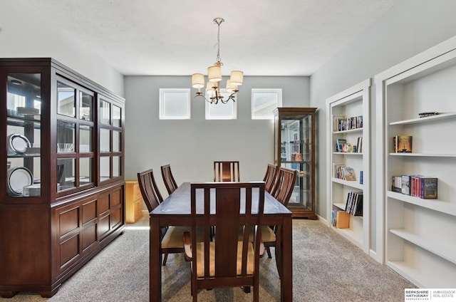dining space with carpet floors, a chandelier, and built in shelves