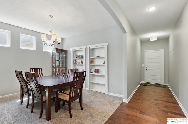 dining area featuring arched walkways, a chandelier, dark wood-type flooring, and baseboards