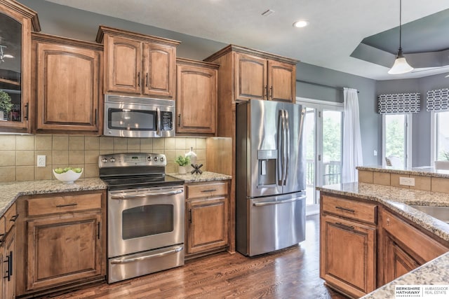 7309 S 196th Cir, Gretna, NE 68028 - kitchen with stainless steel appliances, light stone counters, brown cabinetry, decorative light fixtures, and recessed lighting