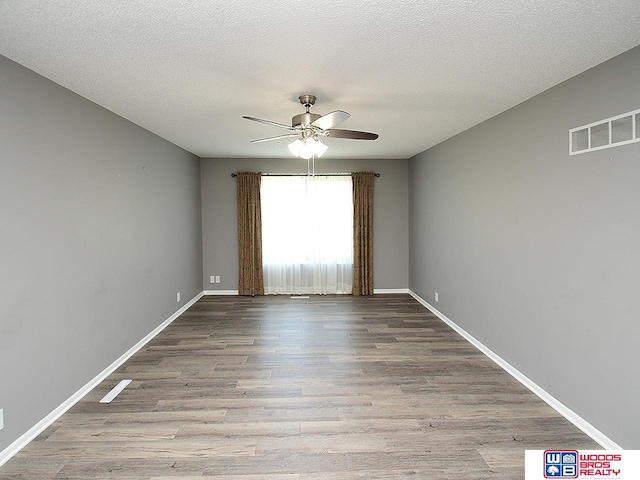 unfurnished room featuring ceiling fan, wood finished floors, baseboards, and a textured ceiling