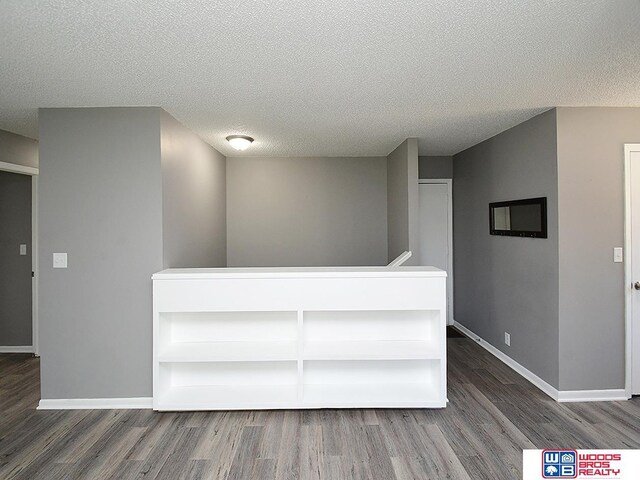 unfurnished room featuring wood finished floors, baseboards, and a textured ceiling