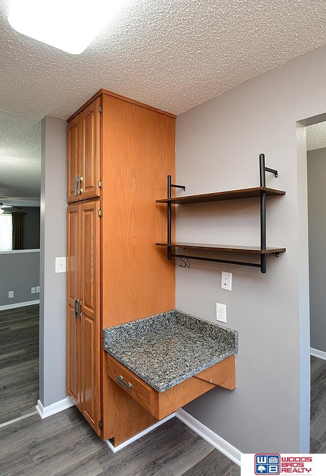 detailed view of a textured ceiling, wood finished floors, and baseboards