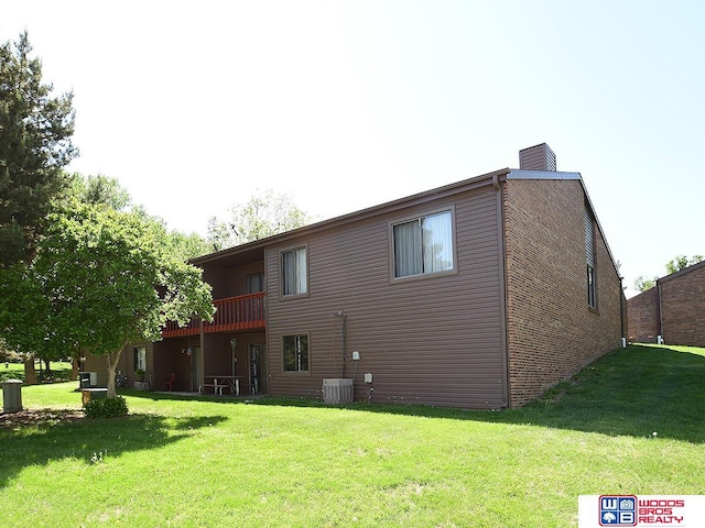 rear view of house with a lawn, a chimney, and central air condition unit