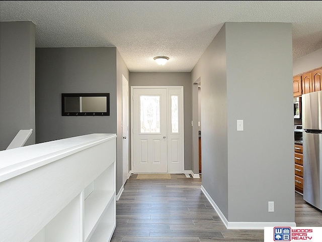 entryway with a textured ceiling, wood finished floors, and baseboards