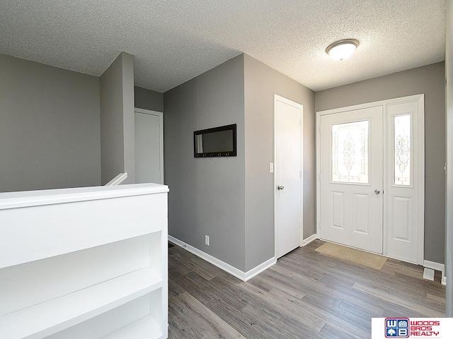foyer featuring wood finished floors, baseboards, and a textured ceiling