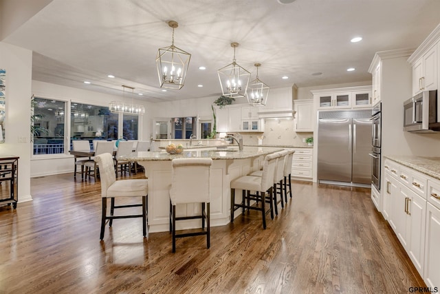 3835 S 179th Ter, Omaha, NE 68130 - kitchen with stainless steel appliances, a chandelier, glass insert cabinets, a kitchen bar, and recessed lighting