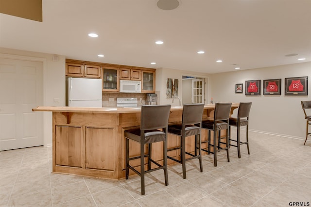 3835 S 179th Ter, Omaha, NE 68130 - kitchen with white appliances, recessed lighting, light countertops, a kitchen bar, and light tile patterned floors