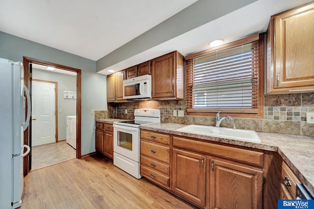 2727 N 75th St, Lincoln, NE 68507 - kitchen with white appliances, a sink, tasteful backsplash, light countertops, and independent washer and dryer