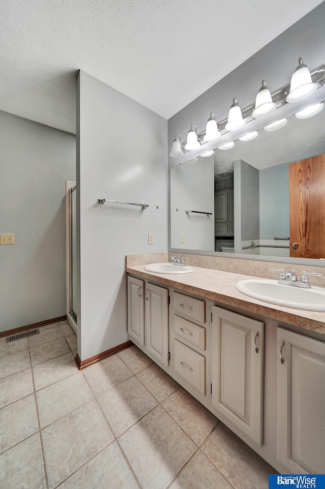 2727 N 75th St, Lincoln, NE 68507 - full bathroom featuring tile patterned flooring, double vanity, baseboards, and a textured ceiling