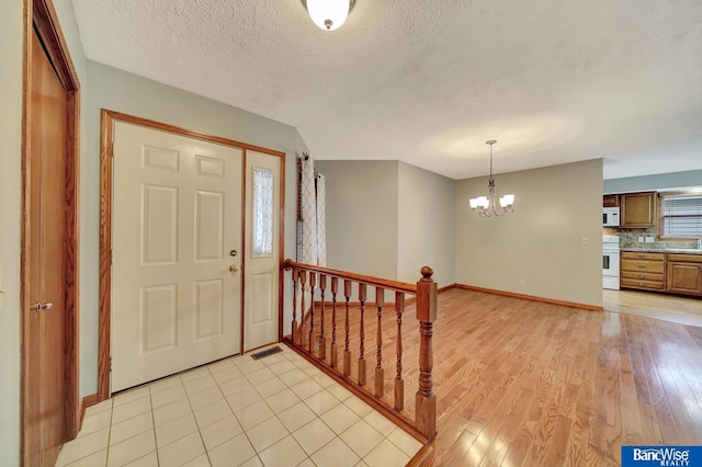2727 N 75th St, Lincoln, NE 68507 - foyer with a chandelier, baseboards, light wood-style flooring, and a textured ceiling