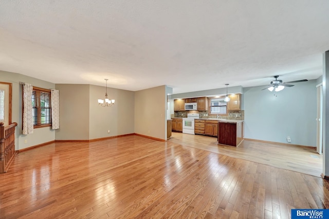 2727 N 75th St, Lincoln, NE 68507 - unfurnished living room featuring a chandelier, light wood-type flooring, baseboards, and a ceiling fan
