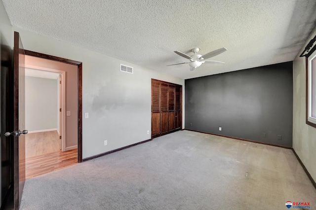 unfurnished bedroom with carpet, a textured ceiling, baseboards, and a ceiling fan