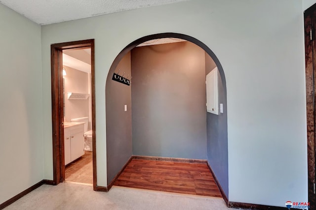 hallway featuring arched walkways and baseboards