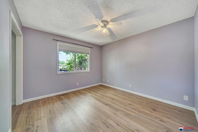 spare room featuring wood finished floors, a ceiling fan, baseboards, and a textured ceiling