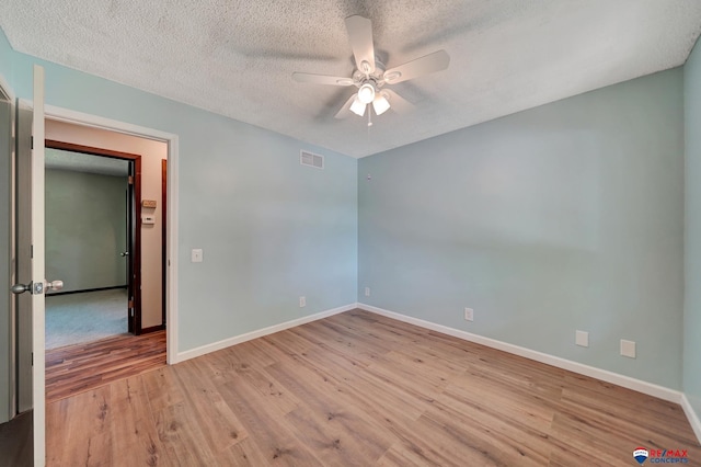 spare room featuring a ceiling fan, wood finished floors, baseboards, and a textured ceiling
