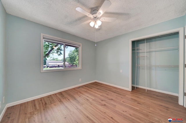 unfurnished bedroom featuring a textured ceiling, wood finished floors, a closet, baseboards, and a ceiling fan