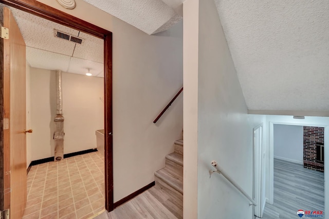stairway with a textured ceiling, baseboards, and wood finished floors