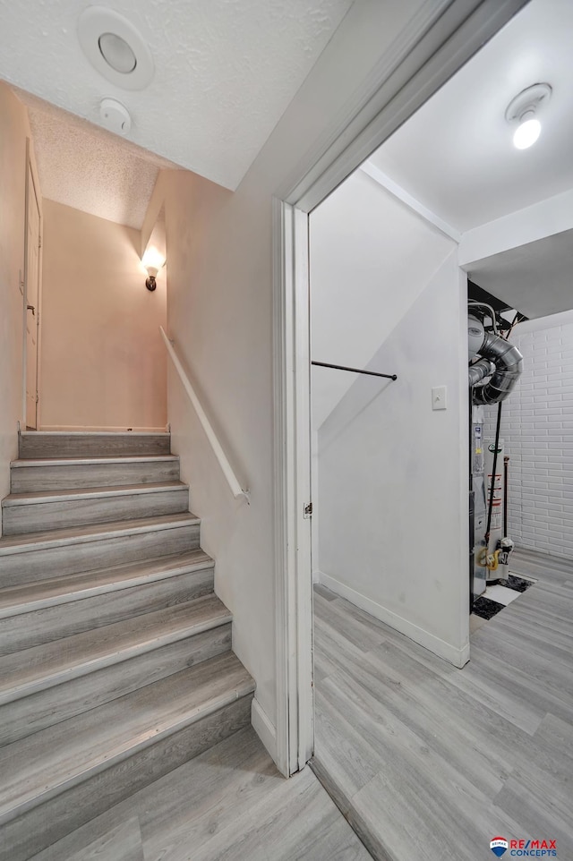 stairway featuring wood finished floors, baseboards, and a textured ceiling